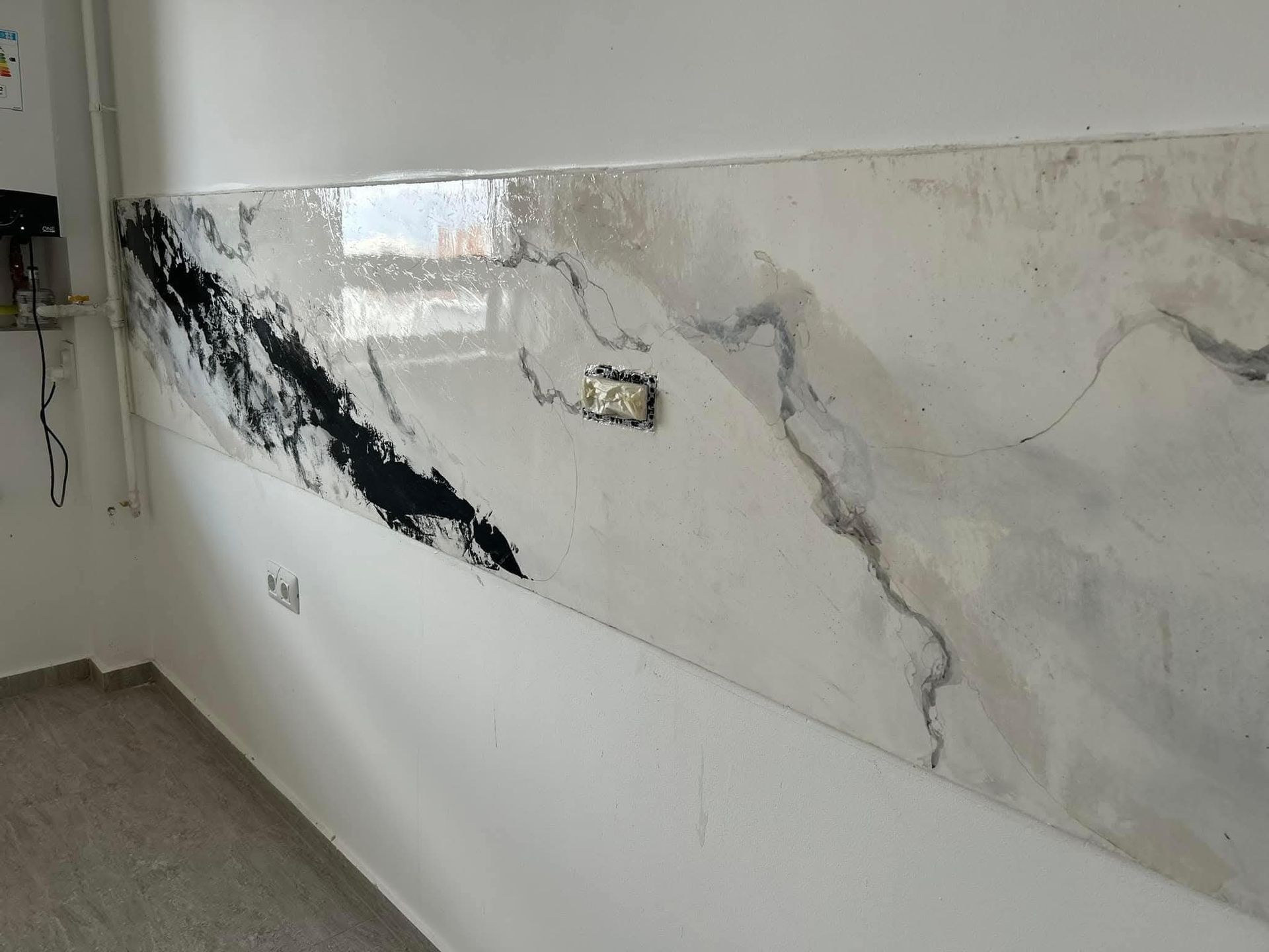Parete in marmo danneggiata con ampie crepe nere e intonaco scrostato in un corridoio interno.
