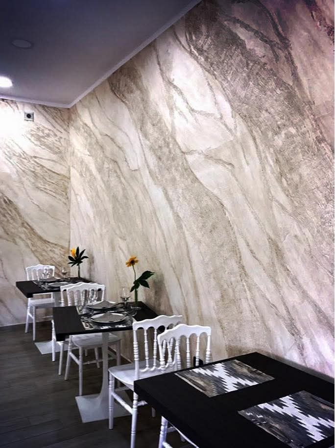 Tavolini da caffè moderni in stile classico, con motivi in ​​bianco e nero, accanto a una grande parete con rivestimento effetto marmo.