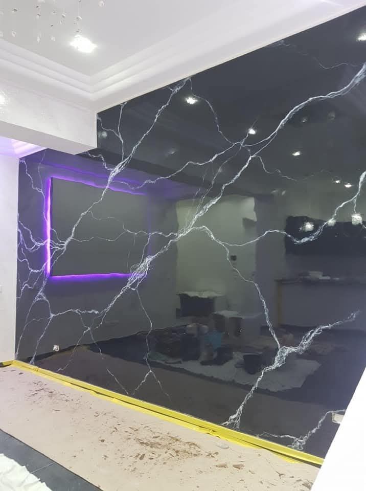 Parete in marmo nero con venature bianche e finiture a LED viola in un interno moderno.
