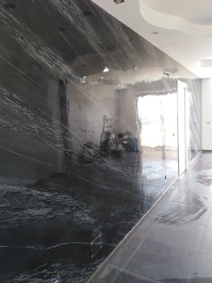 Corridoio rivestito di plastica con una parete nera riflettente e una porta luminosa in fondo