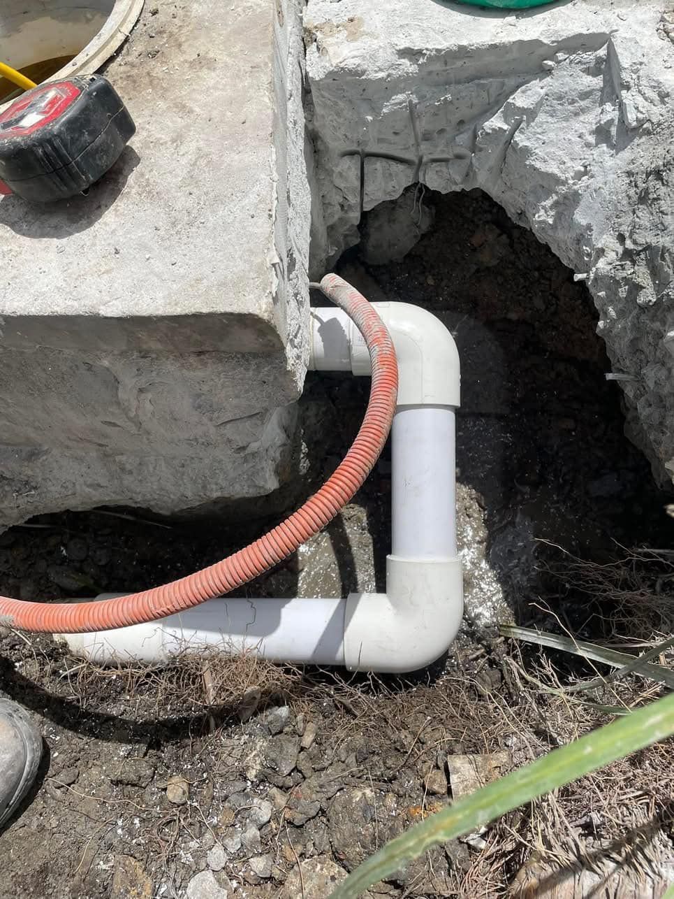 White PVC Pipes and Red Hose Connecting, Set in Dirt and Concrete — Leak N Pool In Southport, QLD