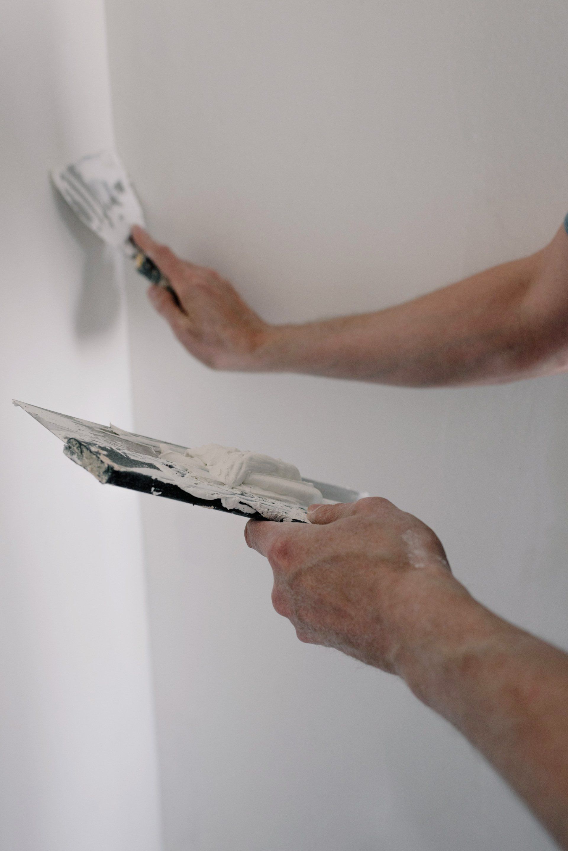 A person applying mud to repair a wall. 