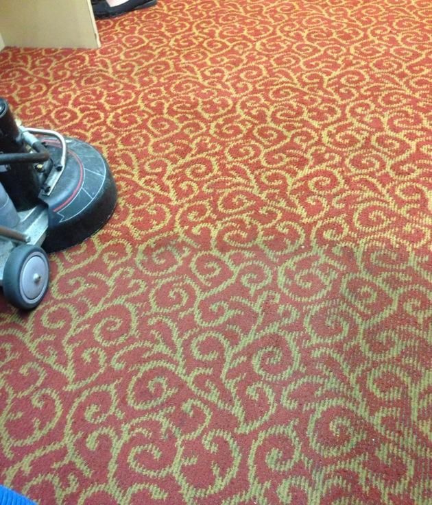 Red patterned carpet with a vacuum cleaner partially visible on the left.