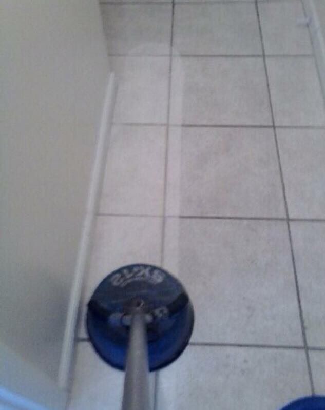 Blue floor cleaning tool on white tiled floor beside a wall