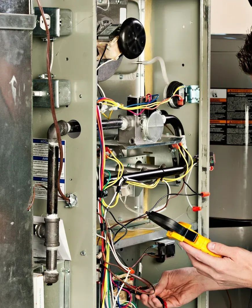 Technician wiring an open electrical panel with tools and multicolored cables