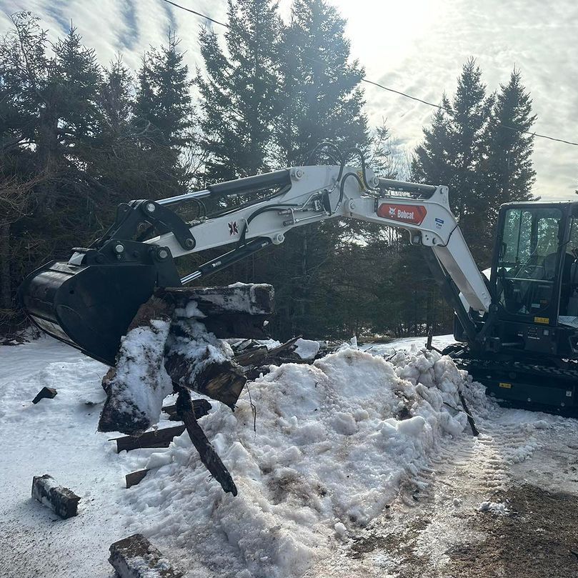 A bobcat excavator is working in the snow
