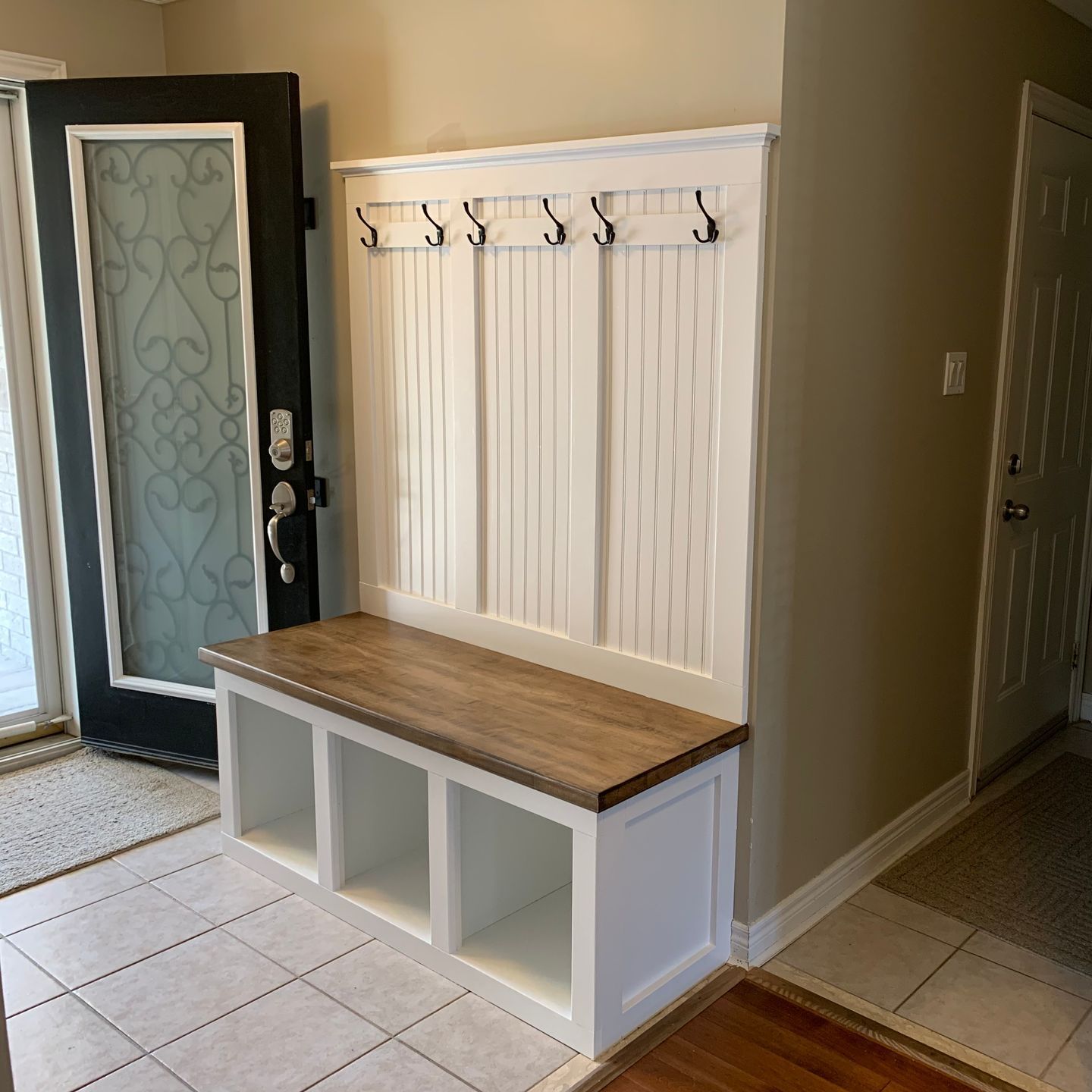 A hallway with a bench and a coat rack.
