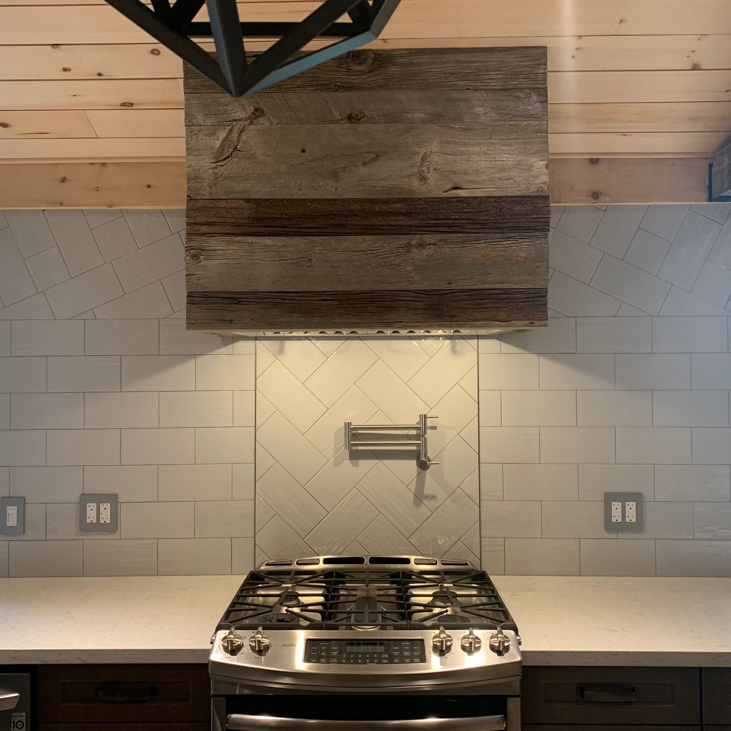 A stove in a kitchen with a wooden hood above it