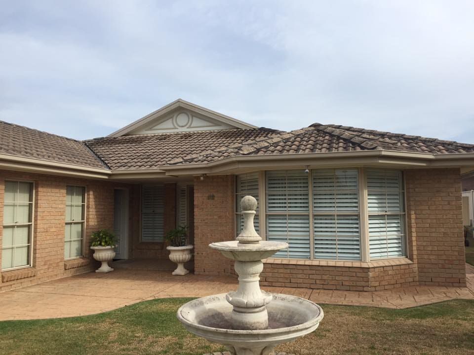 A Brick House with a Fountain in front of it — Roof Repairs in Maitland, NSW