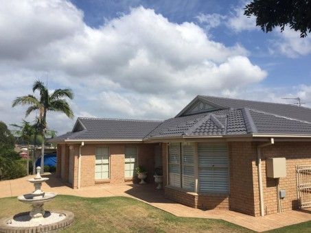 A Large Brick House with a Gray roof and a Fountain in Front of it — Roof Repairs in Maitland, NSW