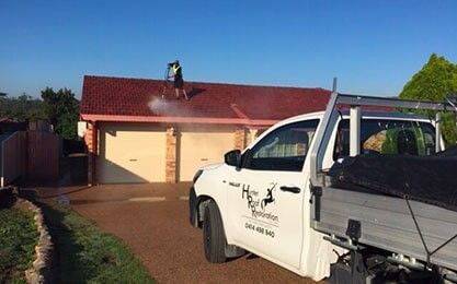A man is Cleaning the roof of a House with a truck — Roof Repairs in Maitland, NSW