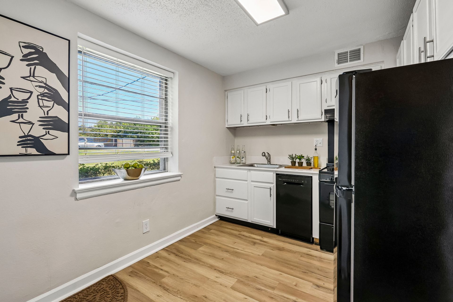 Eat-in kitchen with white cabinetry and wood-style flooring at Brickline Apartments