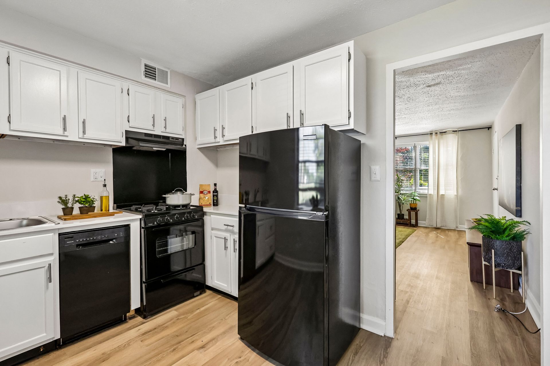 Apartment kitchen with black appliances and a doorway to the living area at Brickline Apartments