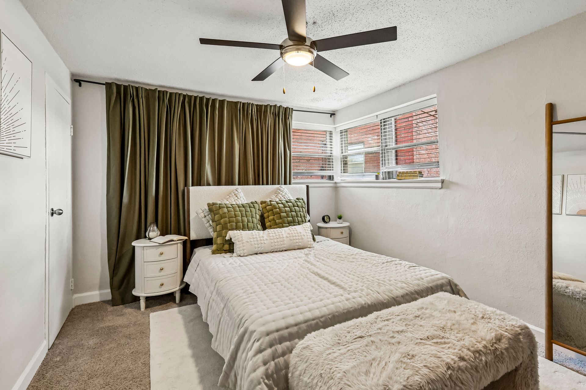 Apartment bedroom with a bed, corner windows, and ceiling fan at Brickline Apartments
