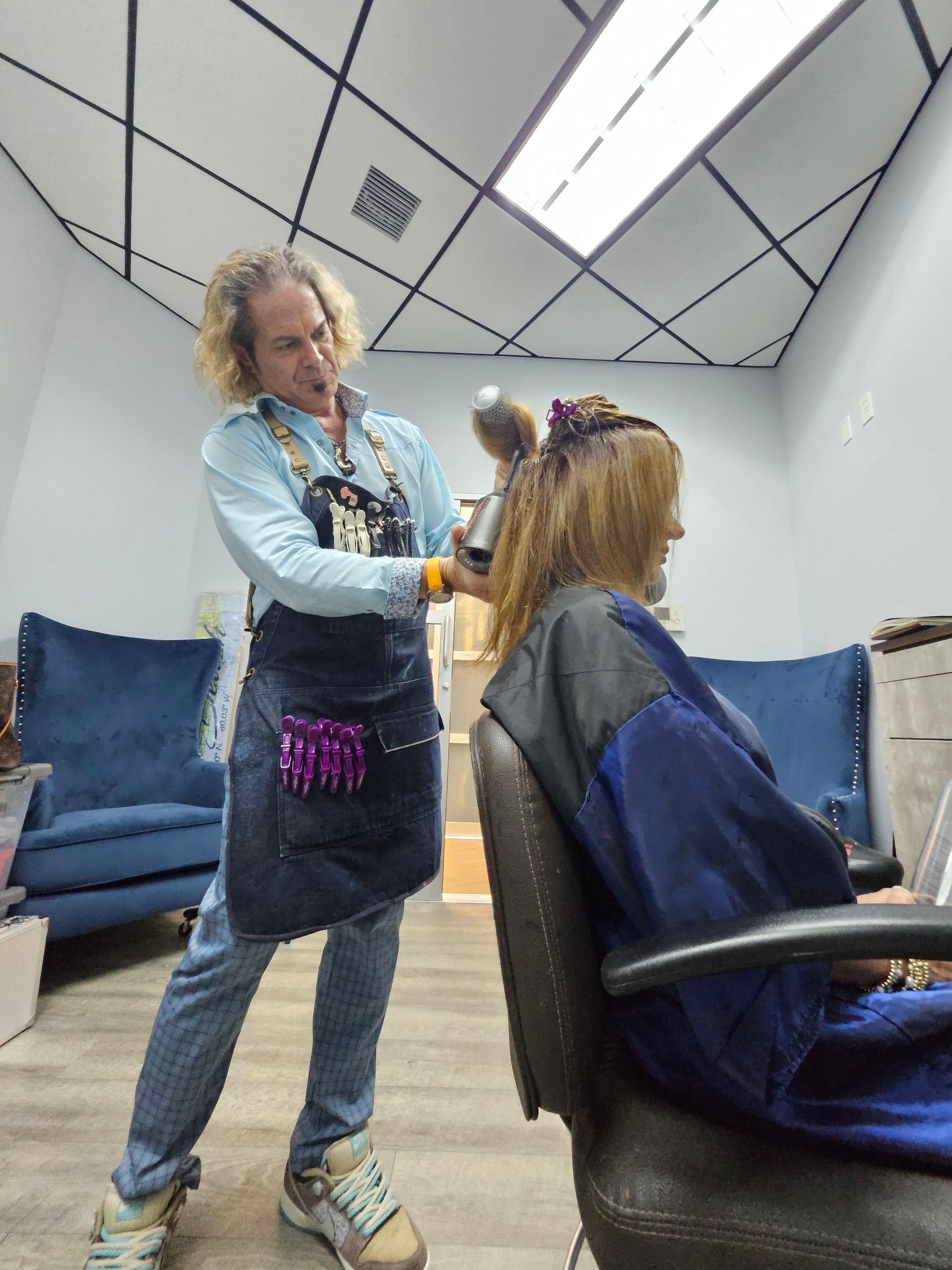 Hair stylist Brian Stencel working on a seated client in a modern salon suite.