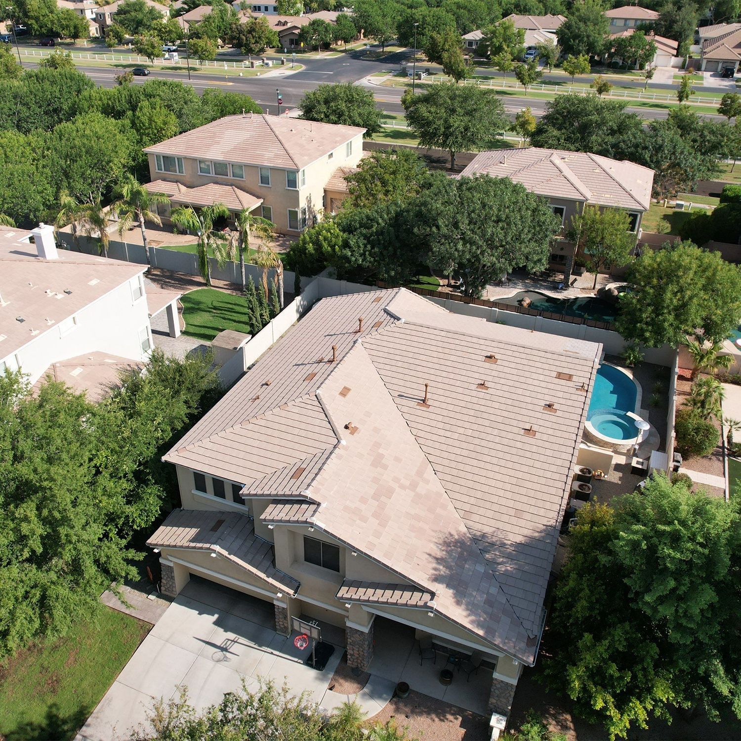 Aerial view of houses with trees, a driveway, and a pool.