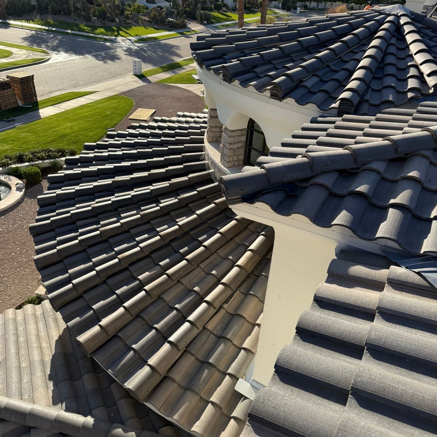 Dark tile roof on a curved building with a view of a street and lawn.