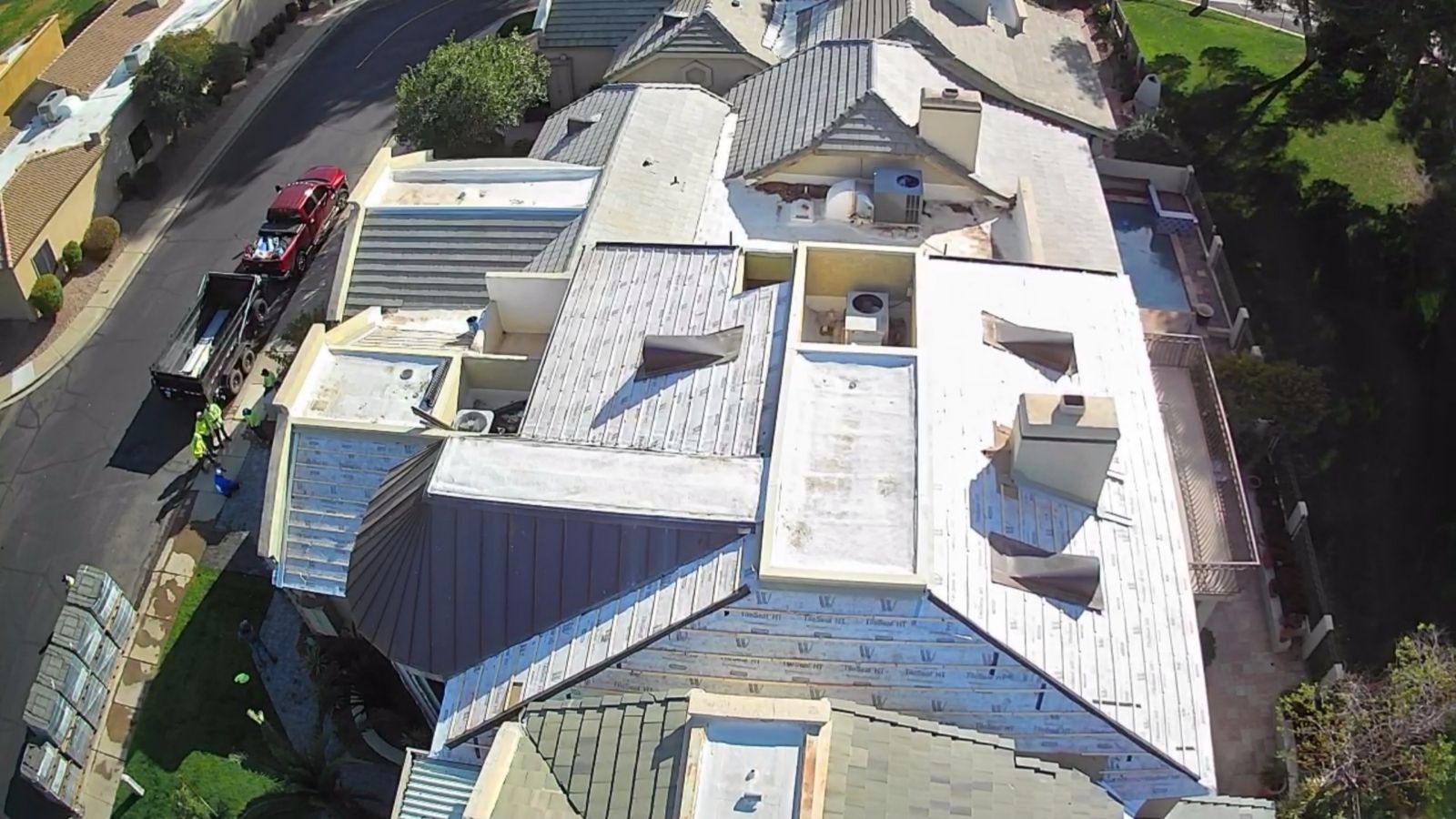 Aerial view of a multi-level home with a complex roof structure, various chimneys, and a delivery truck.