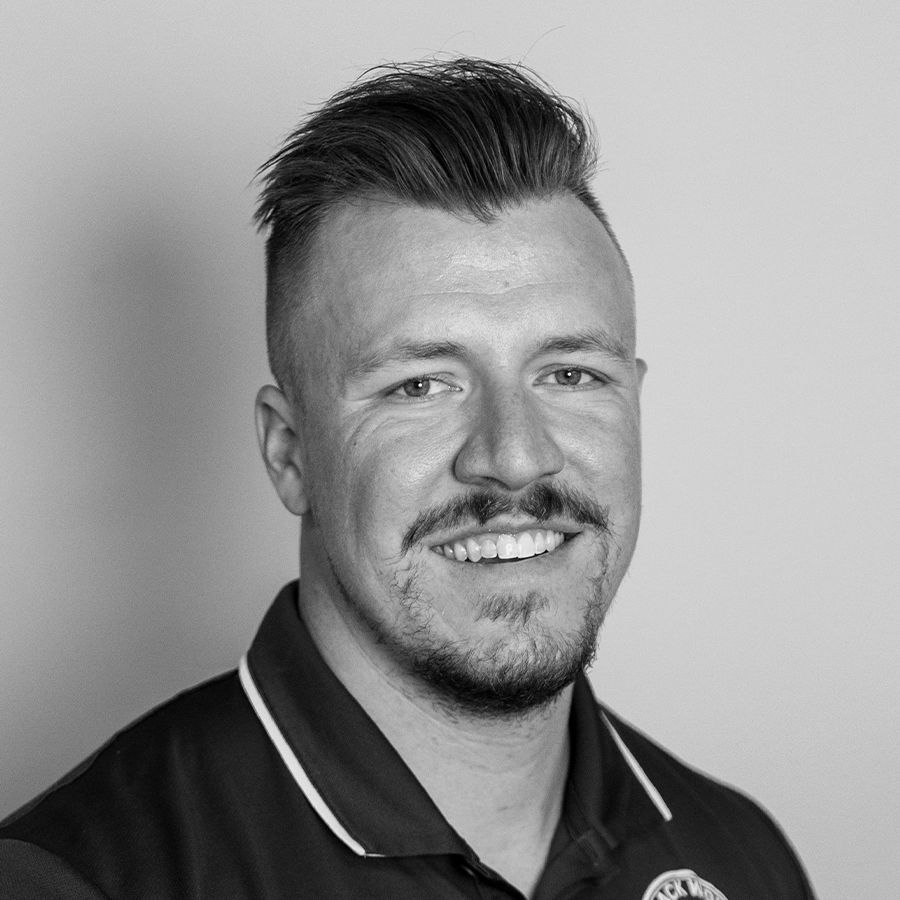 A man with short, styled hair and a goatee smiles, wearing a polo shirt.