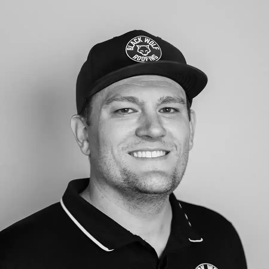 Man wearing a baseball cap and polo shirt, smiling at the camera in a studio.