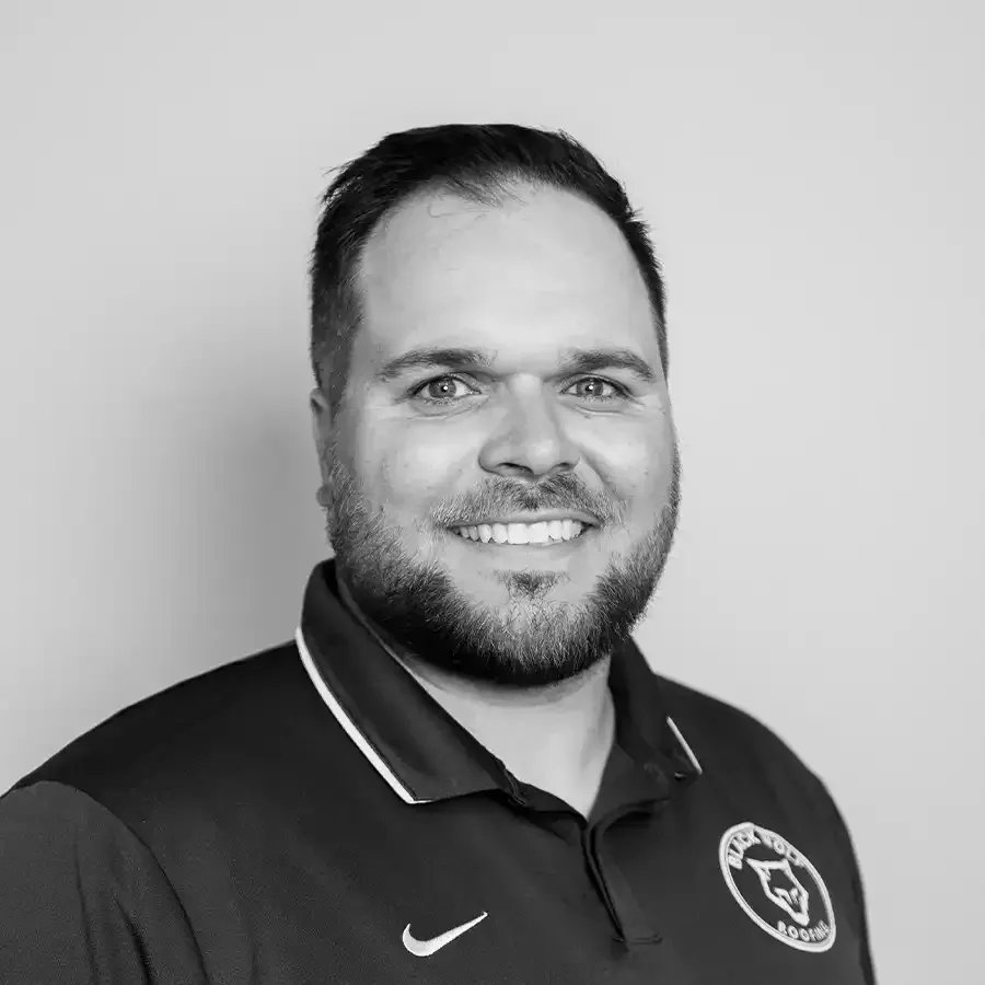 Man with beard smiling, wearing a dark polo shirt with a logo.