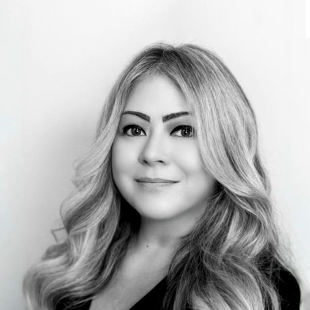 Woman with long, wavy blonde hair smiles at the camera; black and white headshot.