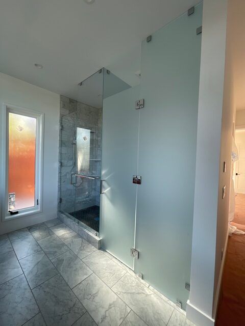 A bathroom with a glass shower door and a window