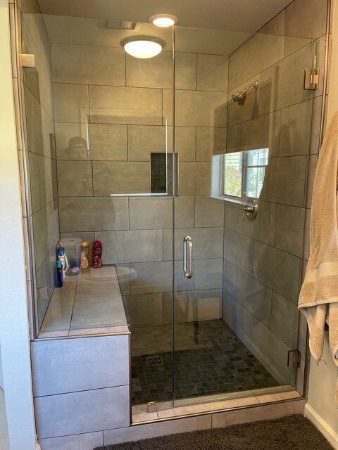 A bathroom with a walk in shower with a glass door.