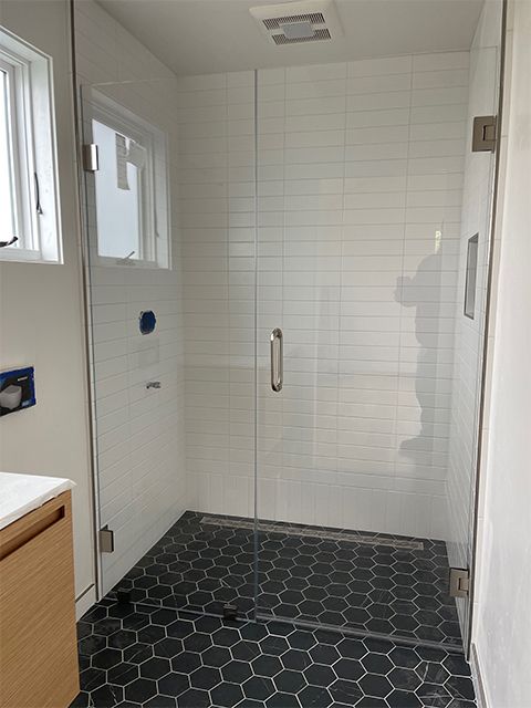 A bathroom with a walk in shower and a black tile floor.