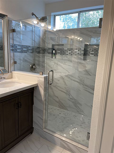 A bathroom with a walk in shower and a sink.