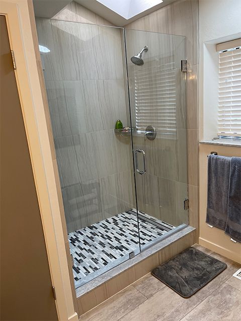 A bathroom with a walk in shower with a glass door.