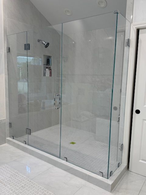 A bathroom with a walk in shower with a glass door.