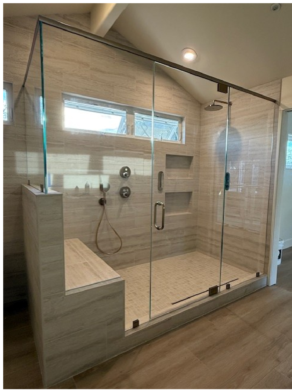 A bathroom with a walk in shower with a glass door.