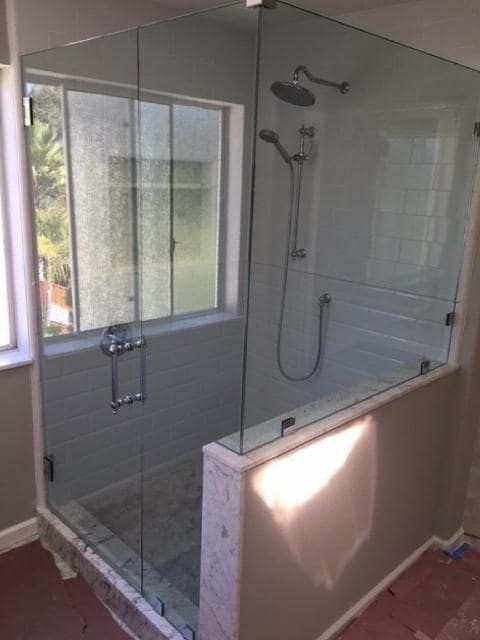 A bathroom with a glass shower door and a window