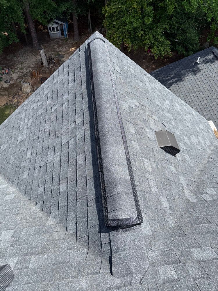Gray shingled roof with a central ridge and a small vent, viewed from above.