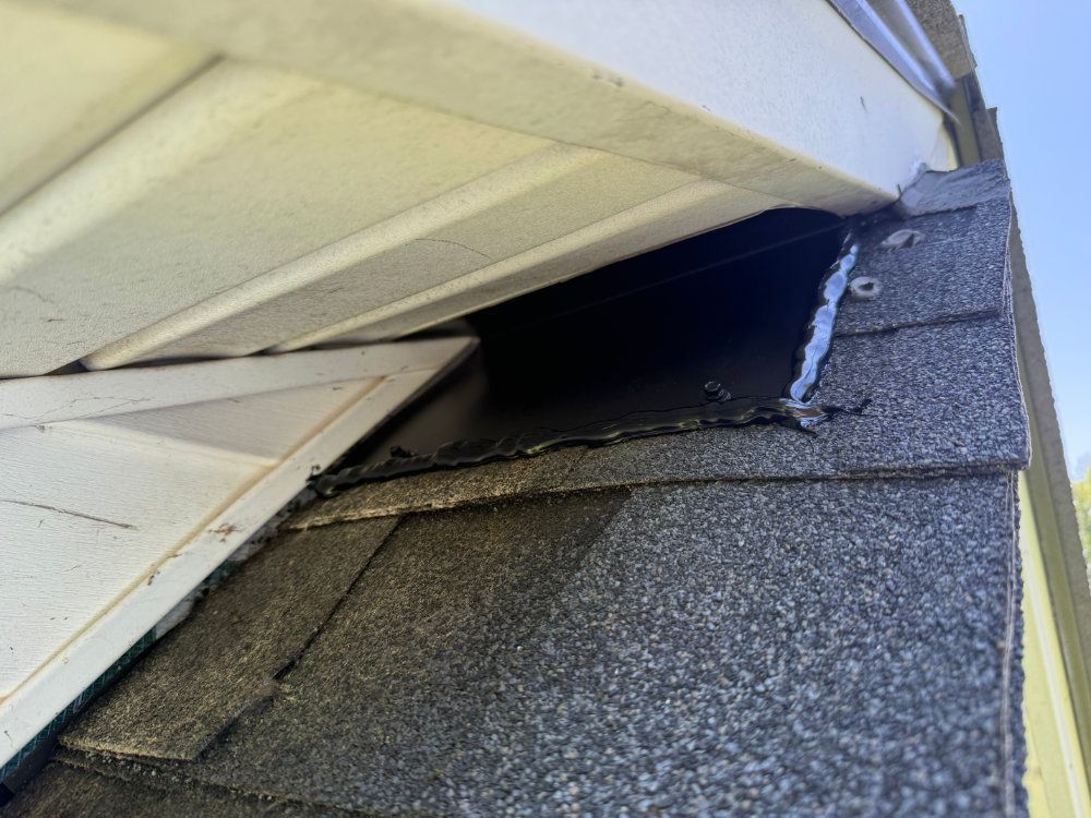 Damaged roof eave with a large gap exposing the underside of the shingles
