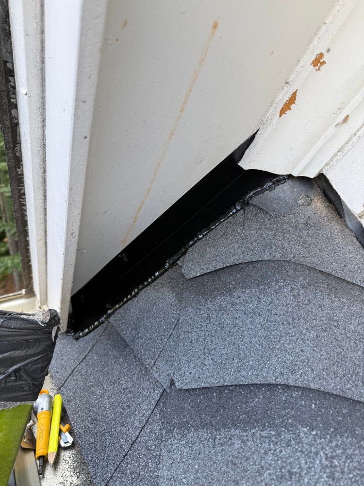 Damaged roof shingles and a gap under white siding near a window frame