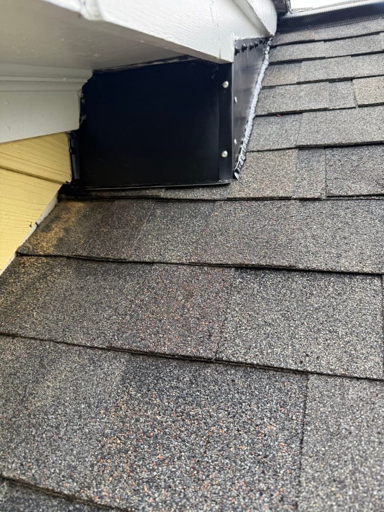 Roof shingles meeting white siding with a black vent opening near the eaves