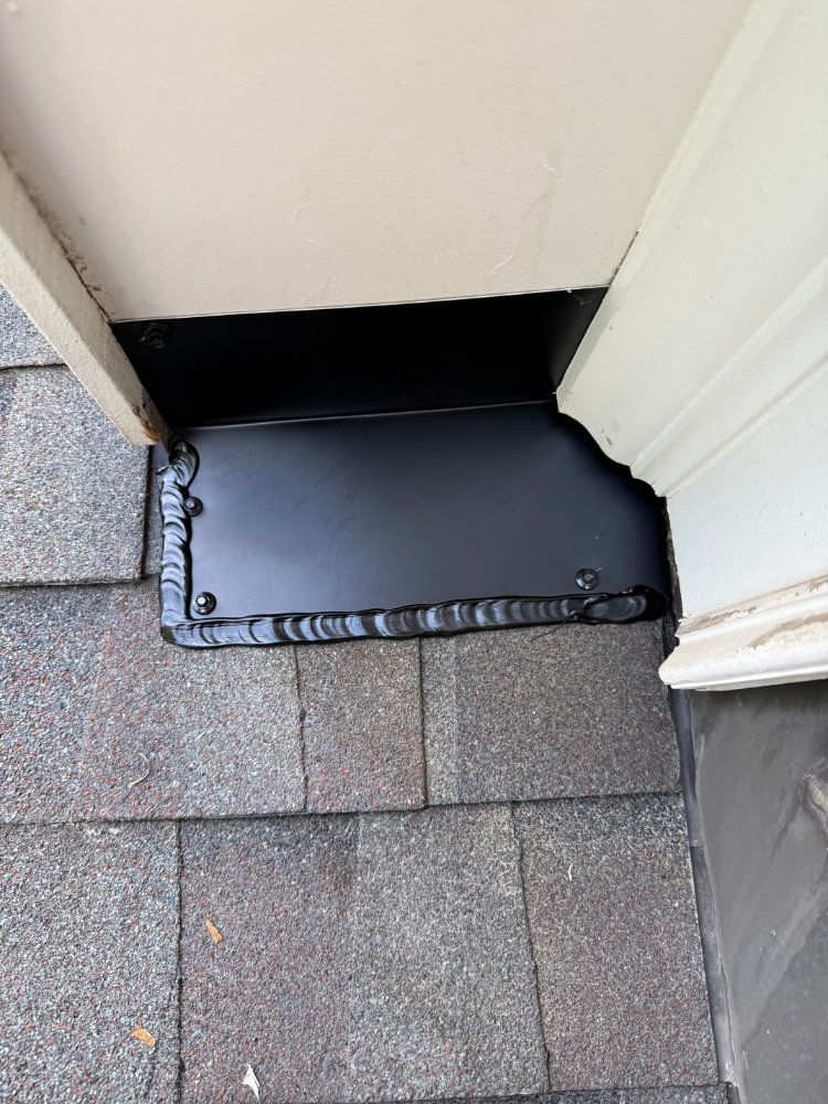 Black cat door mat on gray shingles between a doorway and wall