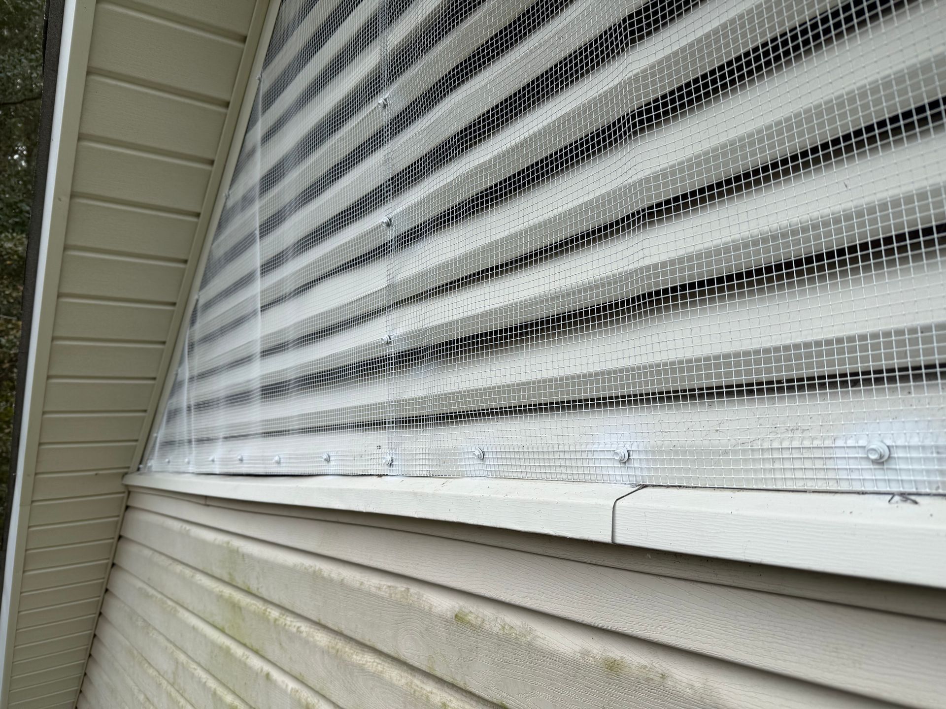 Close-up of white porch siding and a screened window under a roof overhang