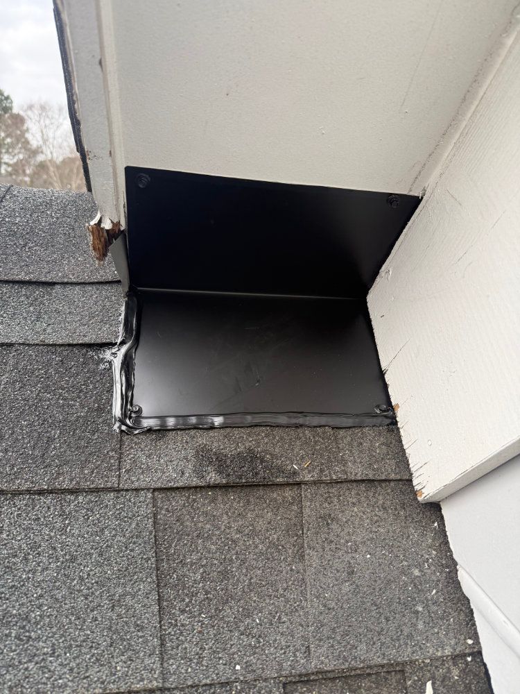 Black metal flashing at roof-to-wall junction above gray shingles and white siding
