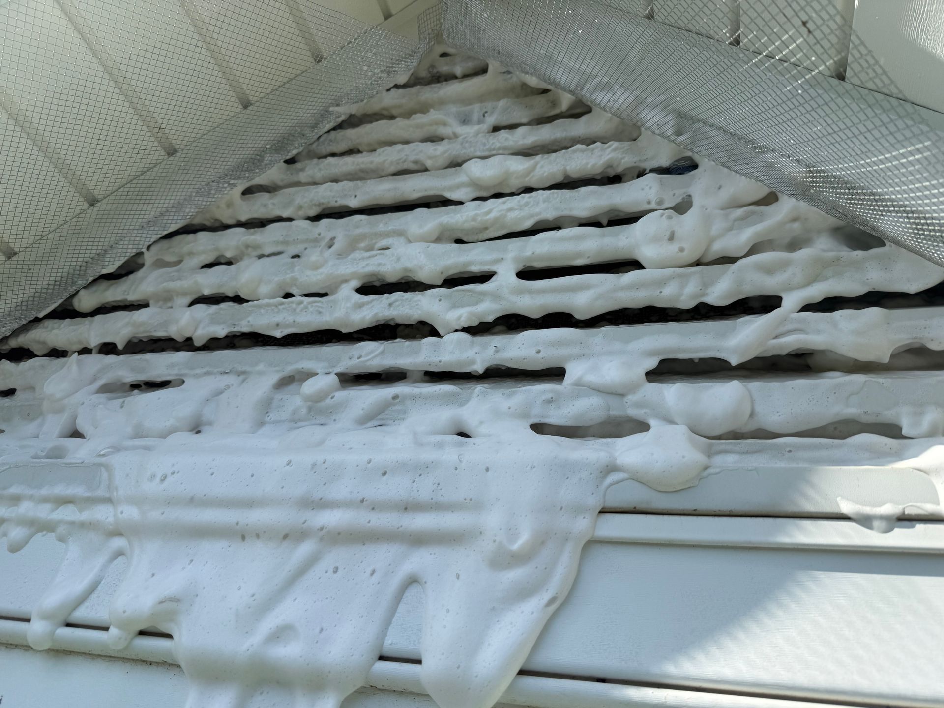 Snow and ice covered slatted roof with icicles hanging under a metal overhang