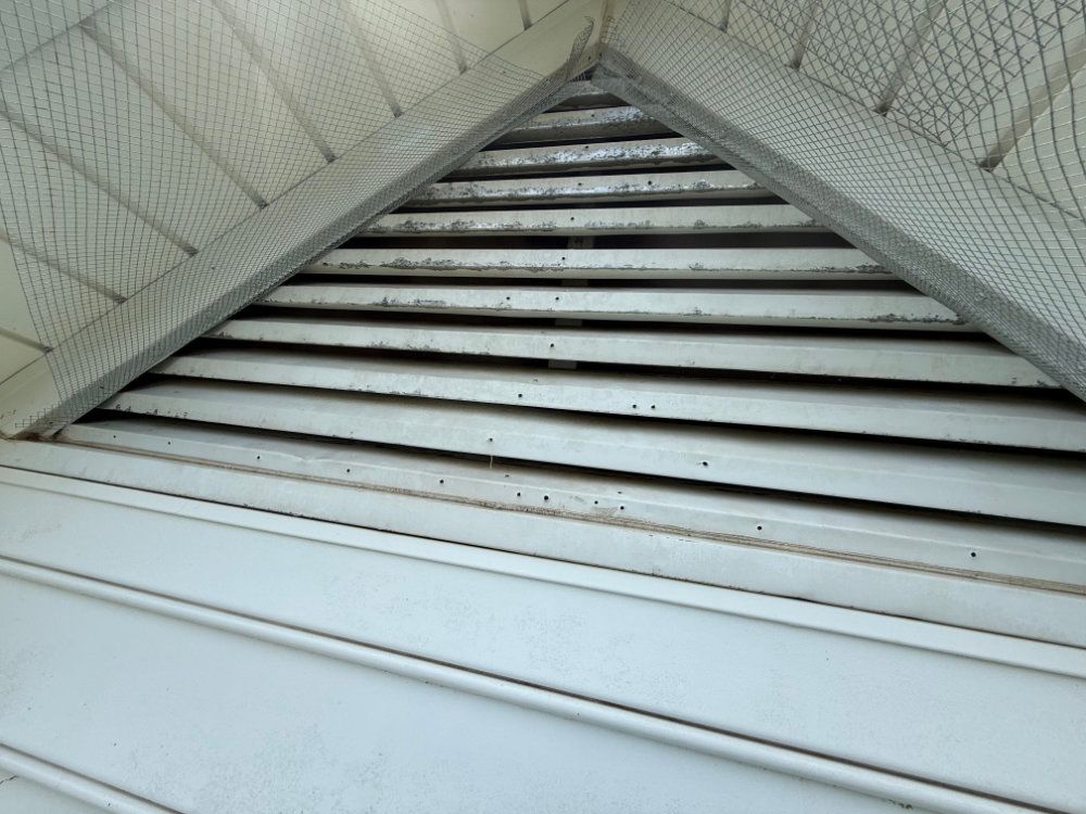 White louvered vent or attic opening framed by a triangular ceiling.