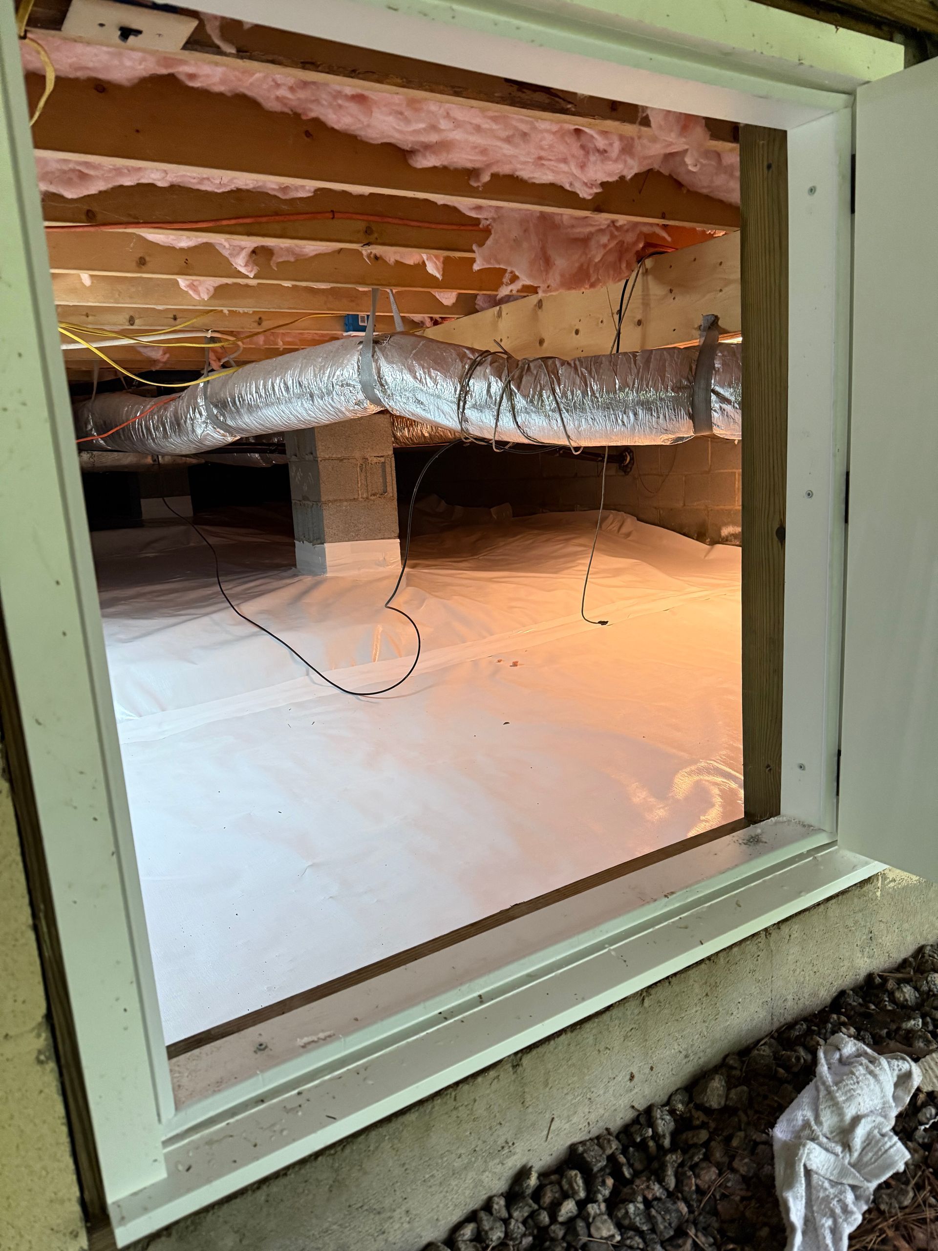 Open window into an attic crawlspace with exposed ducting and insulation