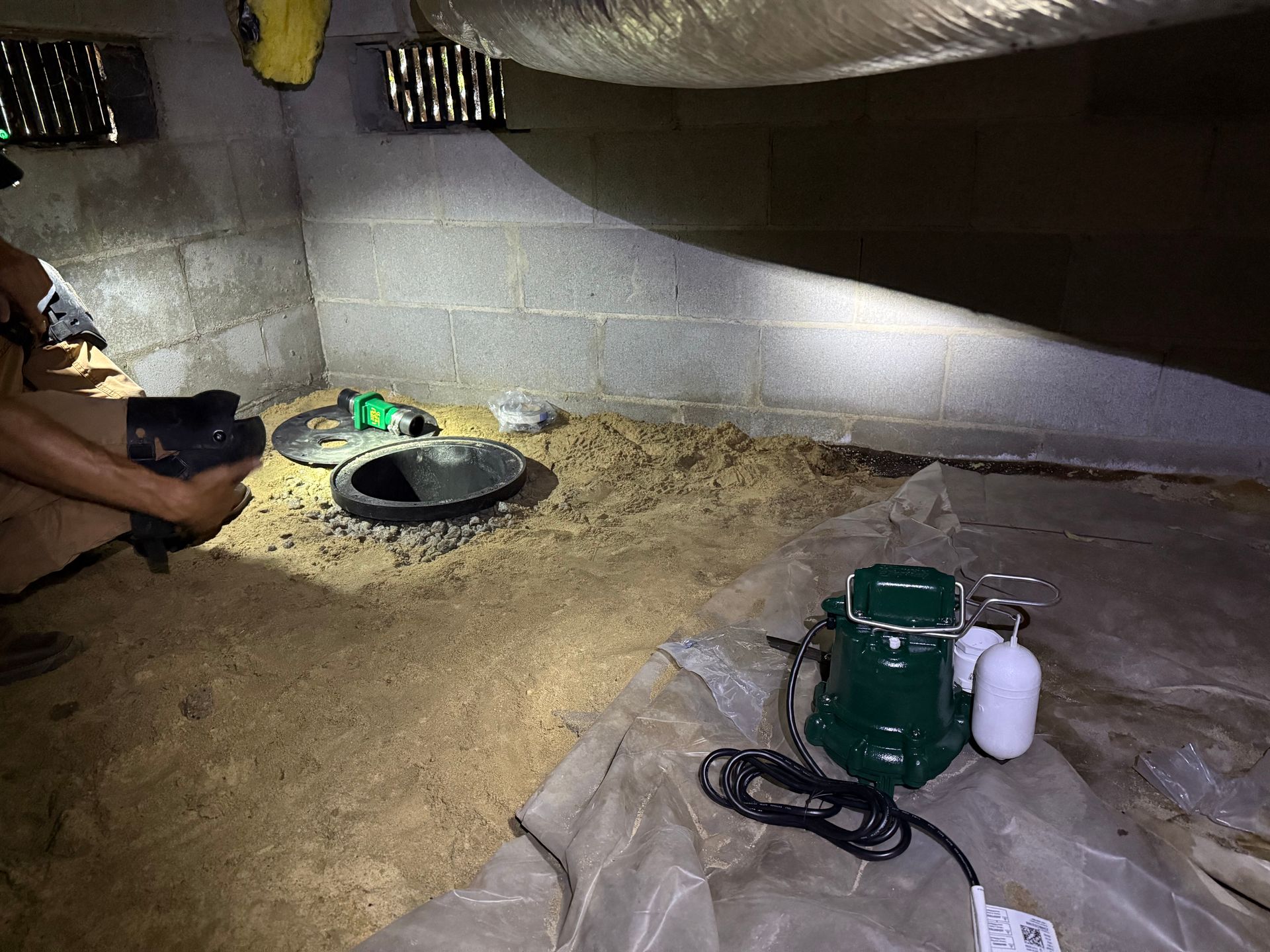Attic crawl space with insulation, two access openings, and tools on the floor.