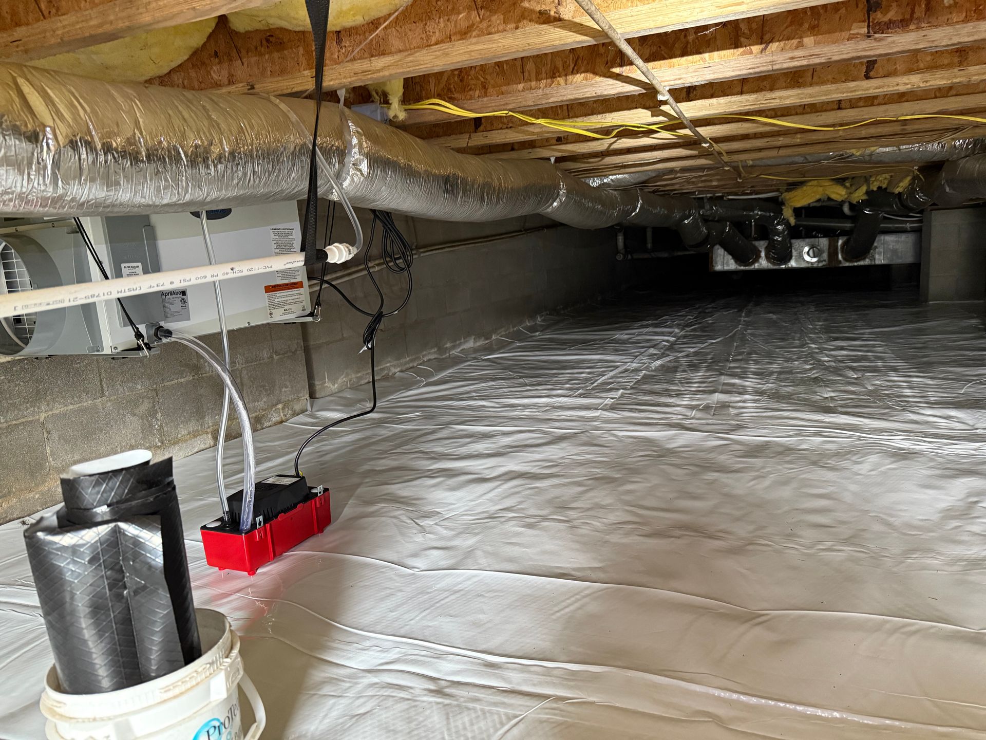 Crawlspace with reflective vapor barrier, exposed floor joists, and HVAC/ductwork overhead