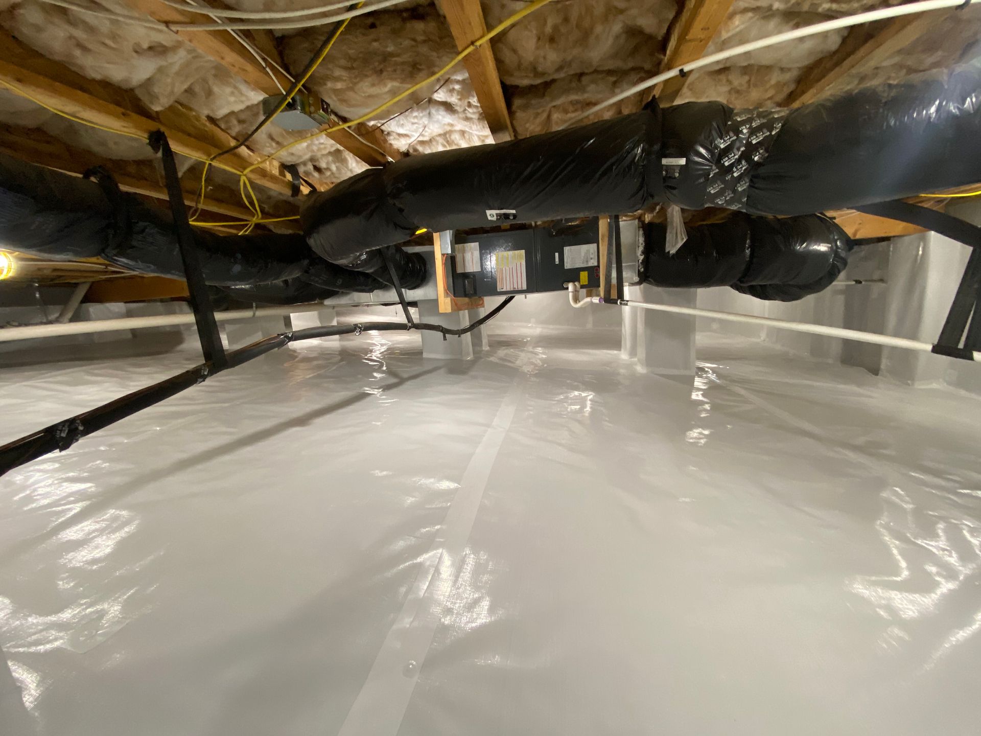Plastic-covered basement crawlspace with exposed insulation, ductwork, and pipes overhead