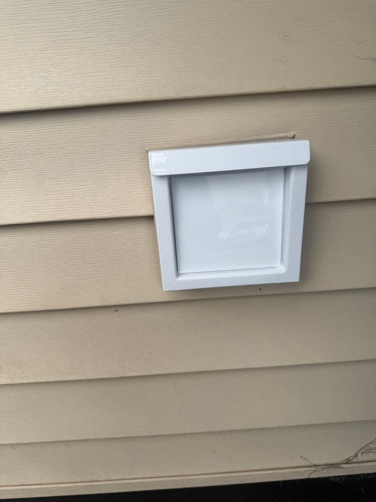 White exterior pet door installed in beige house siding