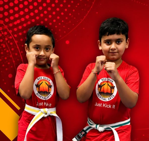 Two children in red martial arts uniforms posing with fists raised against a red background
