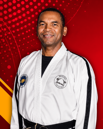 Martial arts instructor in a white gi with patches, smiling against a red background.